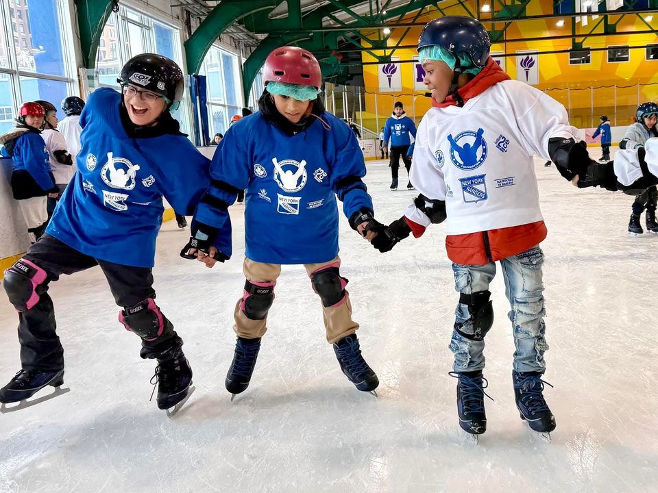 Three North Park skaters holding hands on the ice
